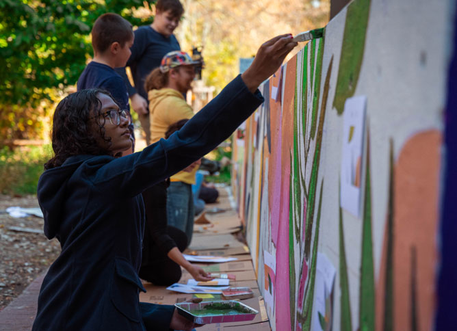 Student painting a mural on Des Plaines campus.