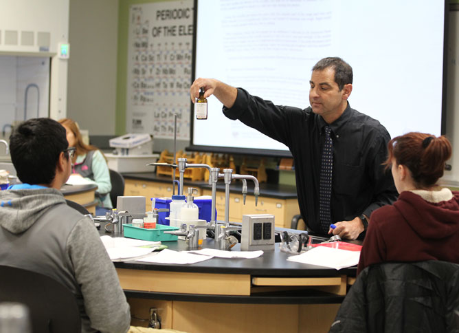 Chemistry teacher holding up a bottle.