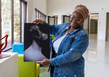 Appears to be woman holding up her painting of a head exploding.